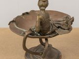bronze statue of a woman sitting on a bowl with a flower in it