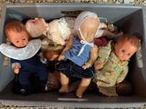 beaucoup de poupées dans une boîte posée par terre