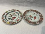 two plates with floral designs on them sitting on a table
