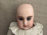 a doll with blue eyes sitting on a couch
