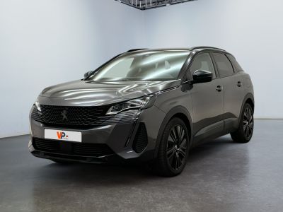 Une voiture grise est garée dans une grande pièce aux murs blancs.