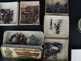 boxes of assorted miniature military items are displayed on a table