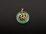 gros plan d'un pendentif vert et or sur une surface noire