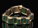 un gros plan d'une bague dorée et verte posée sur une surface noire