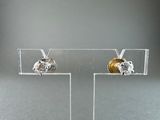 pair of gold and diamond stud earrings on clear acrylic stand