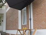 une table et des chaises à l'extérieur d'un bâtiment, surmontées d'un parasol
