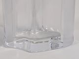 a clear glass vase with a black lid on a white surface
