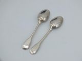 two silver spoons sitting on top of a white table
