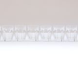 six verres transparents alignés sur une surface blanche
