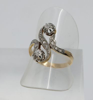 un gros plan d'une bague en or et diamants présentée sur un présentoir transparent