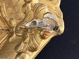 a close up of a gold plate with a bird on it