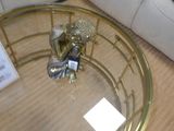 une table basse dorée avec un plateau en verre, sur laquelle est posée une figurine