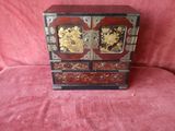 a small wooden cabinet with gold and black decorations on it
