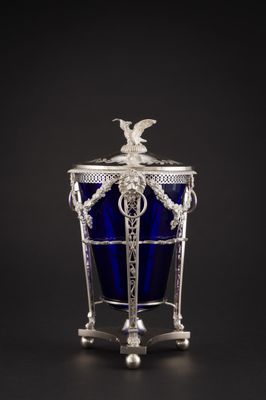 un vase en verre argenté et bleu surmonté d'un oiseau
