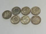 six pièces de monnaie britanniques différentes sont disposées en pyramide sur une surface blanche