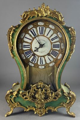 a green and gold clock with roman numerals on it