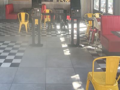 des chaises et des tables aux couleurs vives dans un restaurant au sol à carreaux