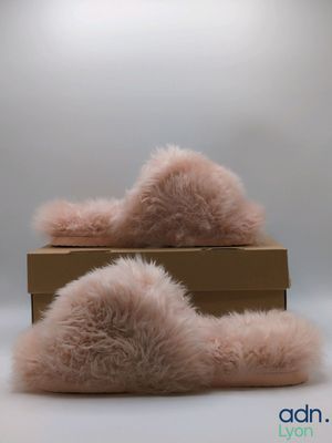pair of pink furry slippers sitting on top of a cardboard box