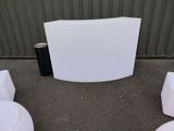 a white curved table with four white stools around it