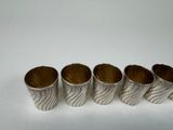 four silver cups with wavy designs are lined up on a white surface