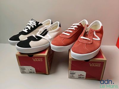 trois paires de baskets Vans posées sur des cartons, sur une table