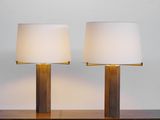 two lamps on a wooden table with a white shade on them