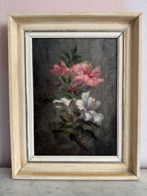 tableau représentant des fleurs roses et blanches, dans un cadre en bois, posé sur une table