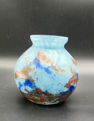 un vase bleu posé sur une table, sur fond noir