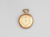 une montre de poche en or exposée sur une surface blanche