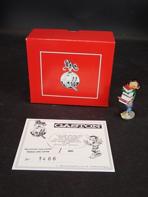 une petite figurine représentant un garçon avec un livre et une boîte rouge