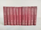 six livres rouges sont alignés sur une surface blanche