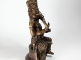 a bronze statue of a man sitting on top of a rock