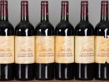 six bottles of red wine are lined up on a table
