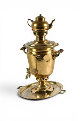 une théière ancienne en laiton posée sur une soucoupe, avec une autre soucoupe en dessous