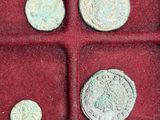 an assortment of ancient coins in a red box on a table
