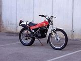 a red motorcycle parked in a parking lot next to a white wall