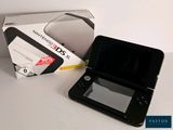 a black nintendo 3ds next to a box on a table