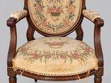 an old chair with a floral upholstered back and a wooden frame