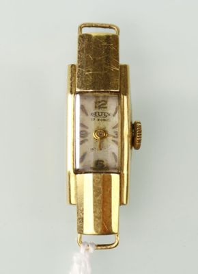 une montre en or accrochée à un mur blanc