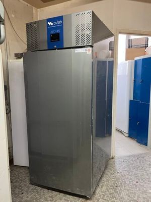 a silver refrigerator sitting in a room with blue lockers