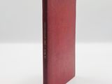 an old red book sitting on top of a white table