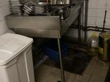 a kitchen with a sink, stove, and trash can in it