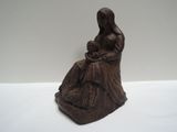 statue représentant une femme assise sur un rocher, tenant un bébé dans ses bras
