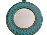 a blue and green circular mirror with a flower design