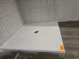 une photo d'une cabine de douche avec un sol en carrelage blanc