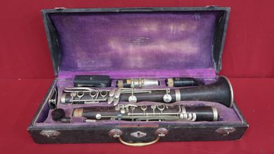 a black and silver clarinet in a case on a red background