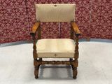 a wooden chair with a beige upholstered seat in front of a red wall