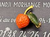 une petite fraise posée sur une plaque sur laquelle se trouve une feuille verte