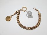 Gros plan sur un bracelet en chaîne en or sur lequel se trouve une pièce de monnaie