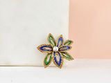 blue, green and gold flower brooch with pearls on a white surface